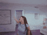 a woman in a blue shirt is standing in a purple room