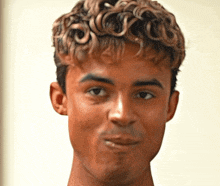 a young man with curly hair looks at the camera