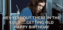 a man with long hair is playing a guitar in front of a microphone in a room .