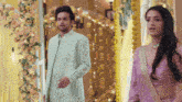 a man and a woman are standing next to each other in front of a door decorated with flowers .