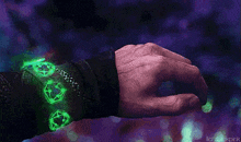 a close up of a person 's hand with a bracelet on it that glows green .