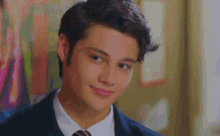 a young man wearing a suit and tie is smiling .
