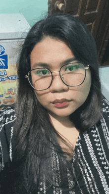 a woman wearing glasses is taking a selfie in front of a sign that says ice-cream