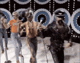 a group of men are dancing on a stage with a microphone in their hand .