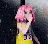 a girl with pink hair is wearing a yellow jersey with the number 32