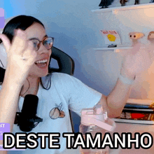 a woman wearing glasses and headphones says " deste tamanho " in front of a pink water bottle
