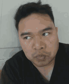 a man in a black shirt is making a funny face with his eyes crossed .