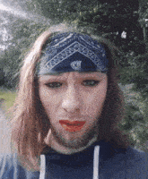 a man wearing a bandana and red lipstick is making a face
