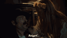 a woman with a flower crown on her head is kissing a man with a mustache and the words babygirl behind them