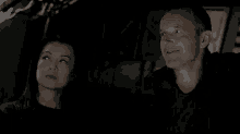 a man and a woman are standing next to each other in the dark .