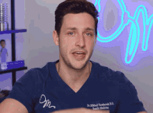 a man wearing a blue scrub top that says dr. mihail plamkowski d.o. family medicine