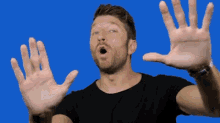 a man in a black shirt is making a funny face with his hands up