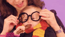 a woman is holding a child wearing glasses and a scarf