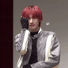 a young man with red hair is covering his face with his hands