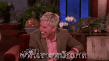 a man in a suit is sitting in a chair and laughing in a room .