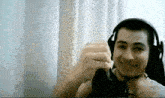 a man wearing headphones is making a funny face while sitting in front of a window .