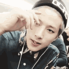 a young man wearing a hat and headphones is taking a picture of himself .