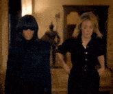 two women standing next to each other in a hallway .