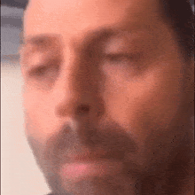 a man with a beard is making a funny face with his eyes closed .