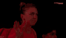 a woman in a red shirt waves her hand in the dark
