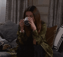 a woman is sitting on a couch drinking from a cup that says ' i 'm sorry ' on it