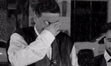 a man in a suit and tie is covering his face in the rain .