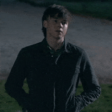 a young man wearing a black jacket and a green plaid shirt