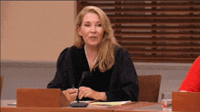 a female judge sits at a table with a microphone