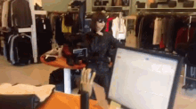 a mannequin is standing in front of a computer monitor in a clothing store
