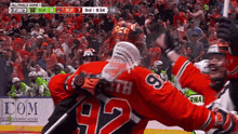 a hockey player wearing a number 92 jersey hugs another player