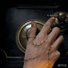 a hand with stitches on it is opening a safe with a netflix logo in the background