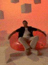 a man sits in a red chair with a red background