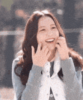 a young woman is making a funny face with her hands while wearing a blue jacket .