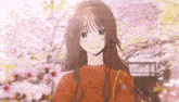 a girl in a red sweater is standing in front of cherry blossom trees .