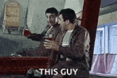 a man is sitting in front of a mirror holding a glass of beer and saying `` this guy '' .