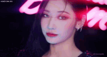 a close up of a woman 's face with a neon sign behind her .