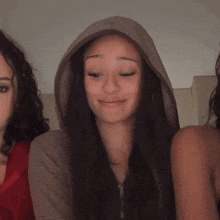 a woman wearing a hooded sweatshirt is making a funny face