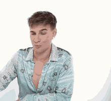 a man wearing a blue paisley shirt with a necklace around his neck