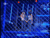 two women are standing in front of a chain link fence .