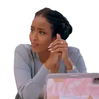 a woman sits at a desk with her hands folded in front of a laptop with a pink case