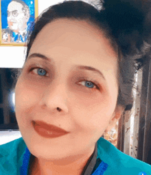 a woman with blue eyes is smiling in front of a painting of a man