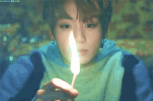 a close up of a person holding a feather in their hand with a flame coming out of it .