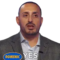 a man in a suit with a blue sticker that says domenic yes