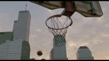 a basketball is going through a basketball hoop in front of a city skyline