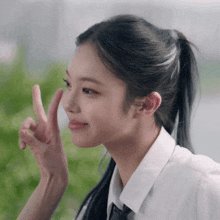 a girl in a white shirt and black tie is giving a peace sign