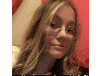 a girl wearing glasses looks at the camera with a red background
