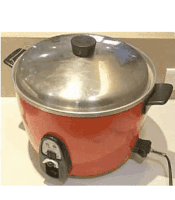a red rice cooker with a stainless steel lid is sitting on a table .