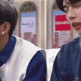 two people are sitting in front of a sign that says suzu