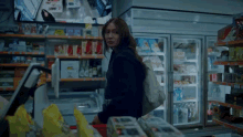 a woman is standing in a grocery store looking at a computer screen .