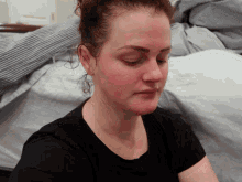 a woman in a black shirt has her eyes closed and her hair in a bun
